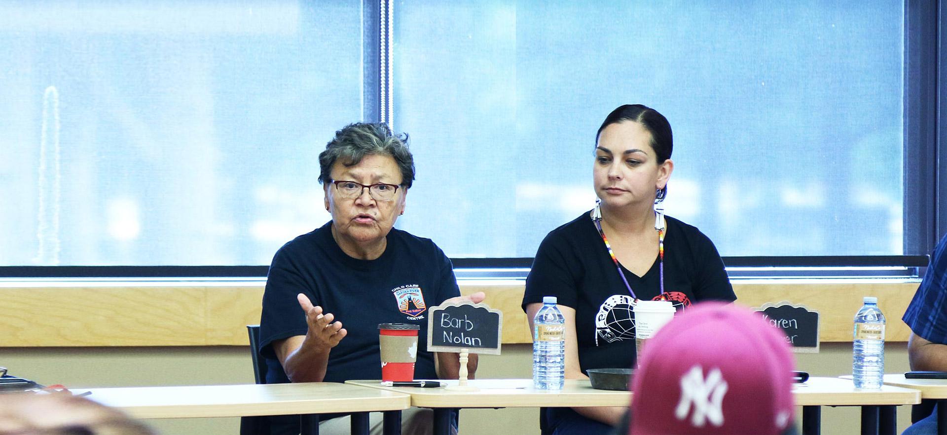 Two female ϲͼȫ Indigenous women conduct a group meeting with Indigenous youth.