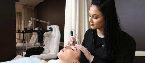 One female Esthetician student applies a skin treatment to another student in the ϲͼȫ salon spa.